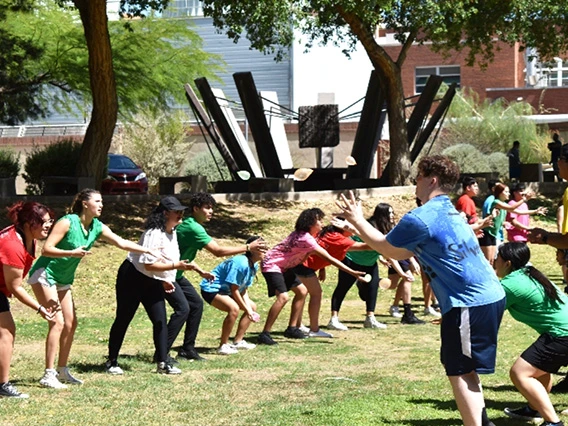 two groups of kids facing each-other throwing water balloons to catch without breaking