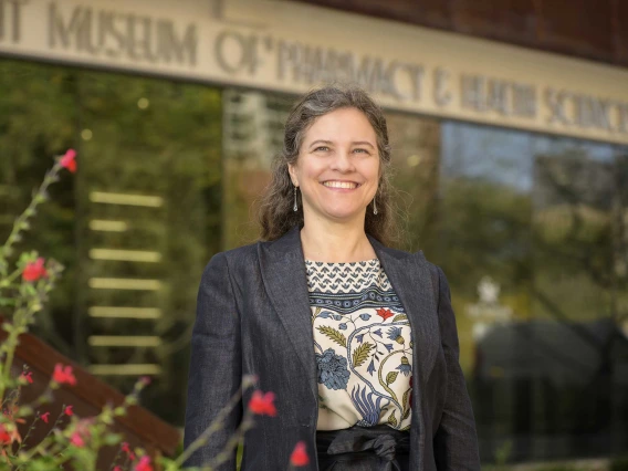 A woman smiles as she stands outside in front of a museum.