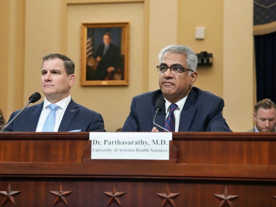 Dr. Sairam Parthasarathy sitting behind a name placard and microphone at a government committee hearing