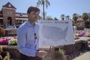 A student walks past a map of the United States that shows the places where students will conduct their residency training.