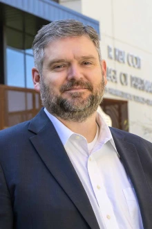 Portrait of Nathan Cherrington, PhD, standing outside wearing a blue sport coat.