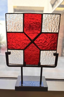 Photo of a stained glass red cross set on a metal stand.